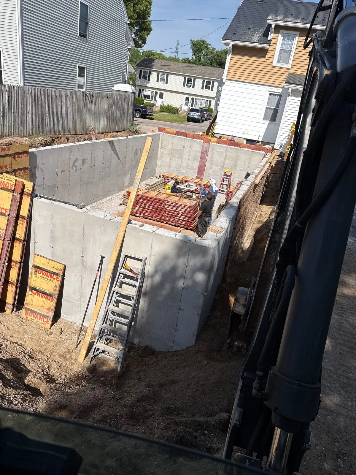 Foundation walls beside an excavator on a tight urban lot