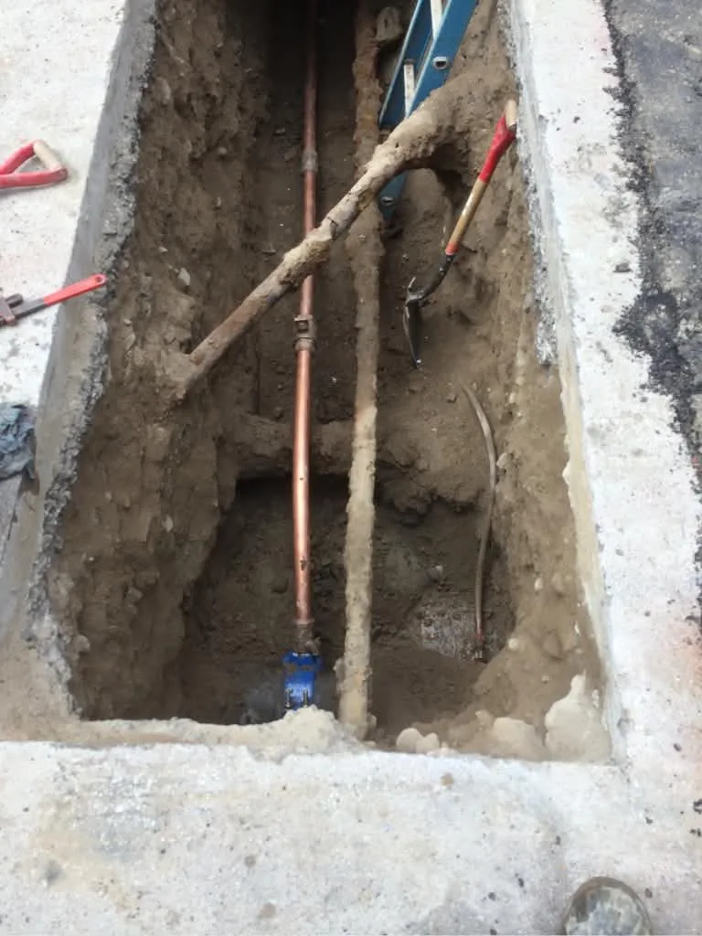 Excavated trench showing a water service line and valve
