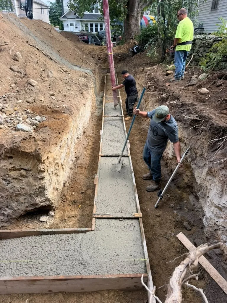 Crew placing concrete in footing forms