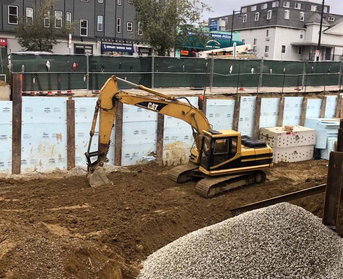 An excavator working inside a shored urban job site