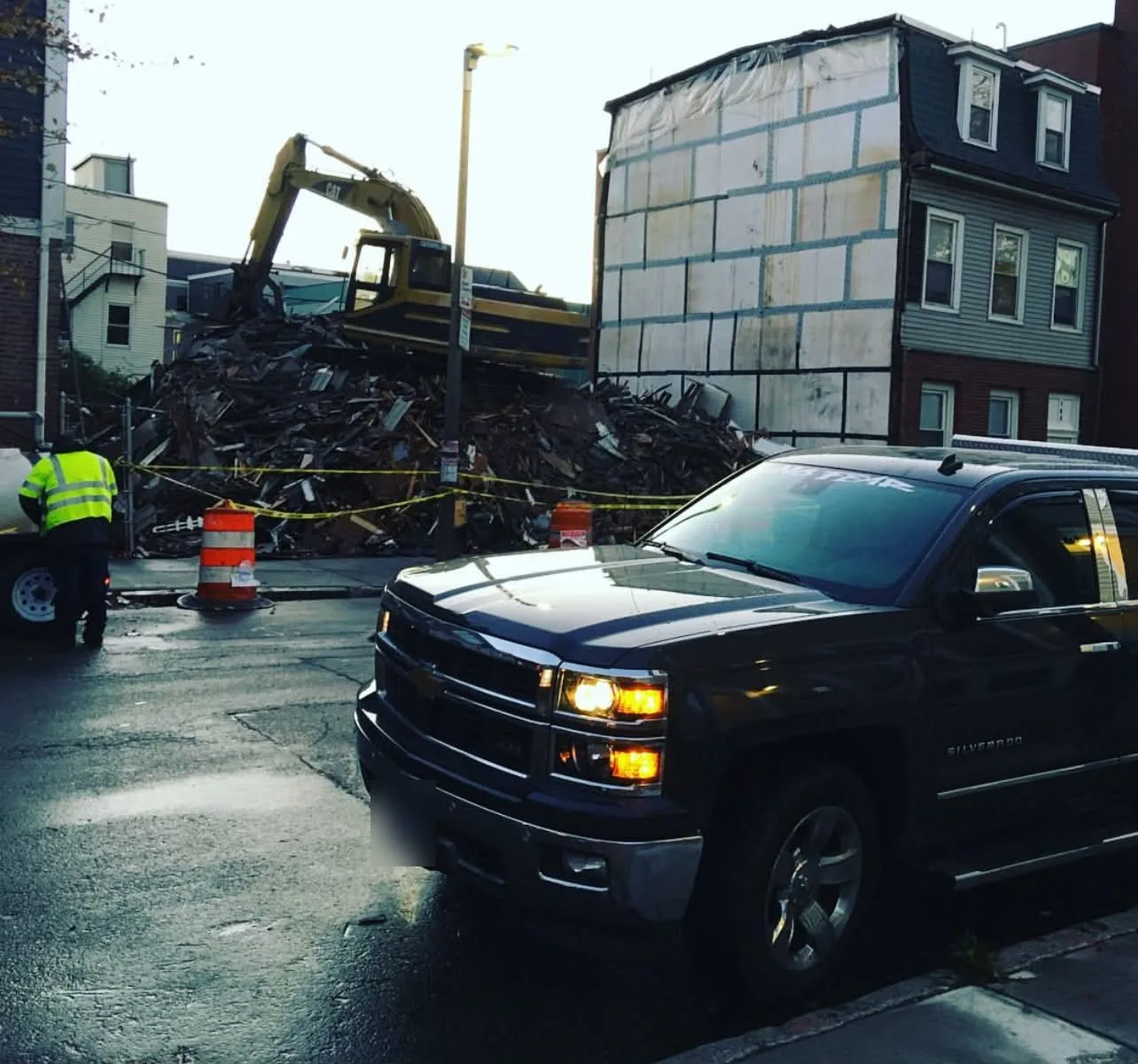 Demolition debris and an excavator on an urban lot