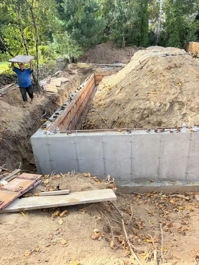 A finished foundation wall with form panels stacked nearby