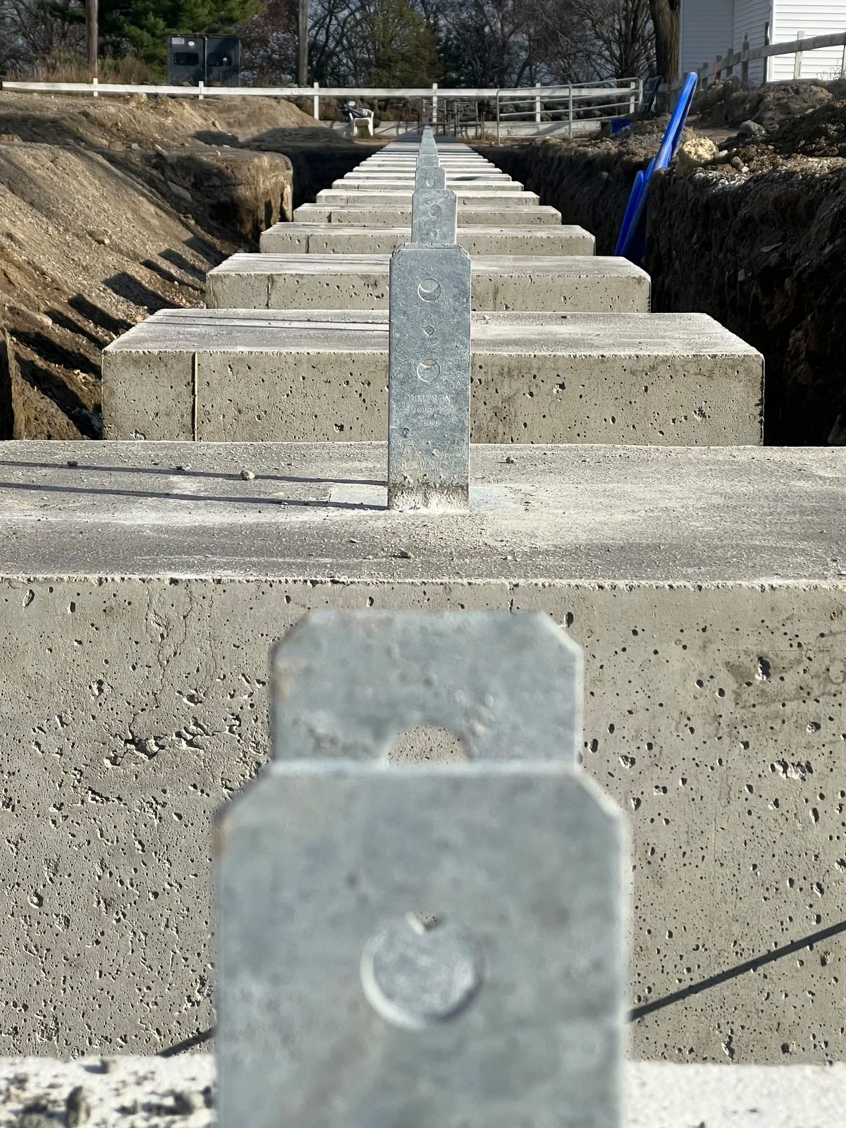 Row of concrete pier footings with steel brackets